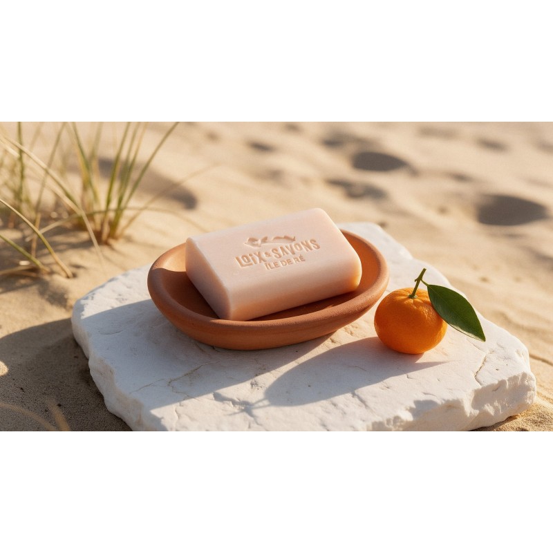 savon artisanal soleil et dunes rose peche dans un porte-savon terracotta avec une mandarine