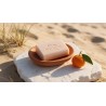 savon artisanal soleil et dunes rose peche dans un porte-savon terracotta avec une mandarine