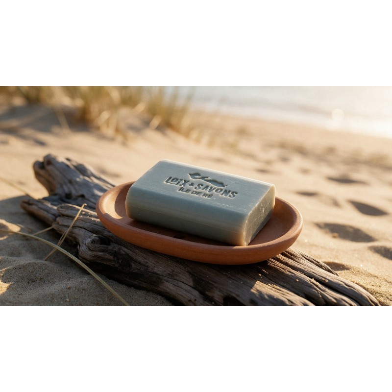 savon artisanal bois flotte gris clair dans un porte-savon terracotta sur du bois flotte