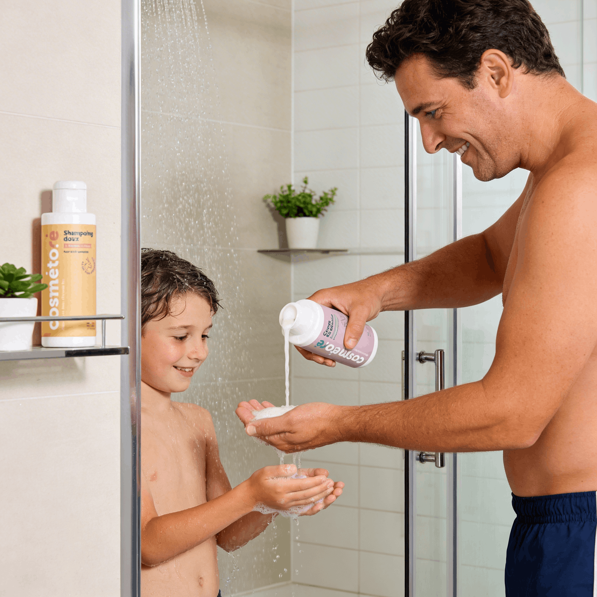 Père versant la crème douche au lait d'ânesse dans les mains de son fils sous la douche