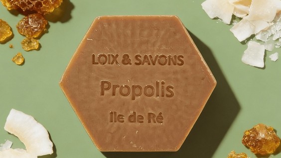 Savon hexagonal à la propolis avec rayons de miel et copeaux de noix de coco sur fond vert sauge